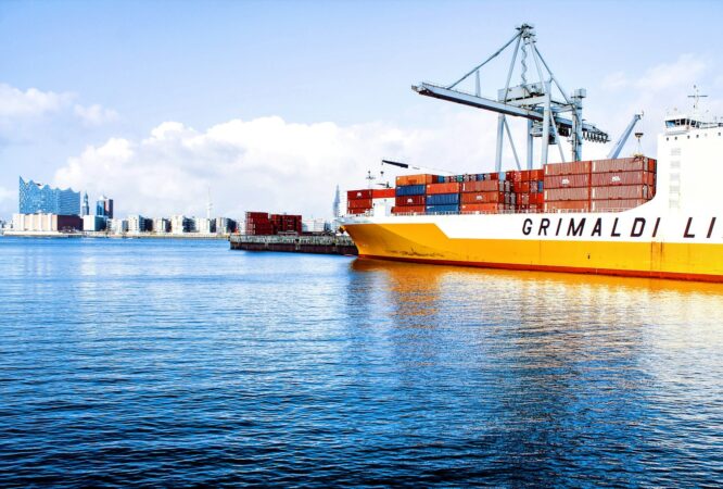 white and orange cargo ship with metal lifting equipment